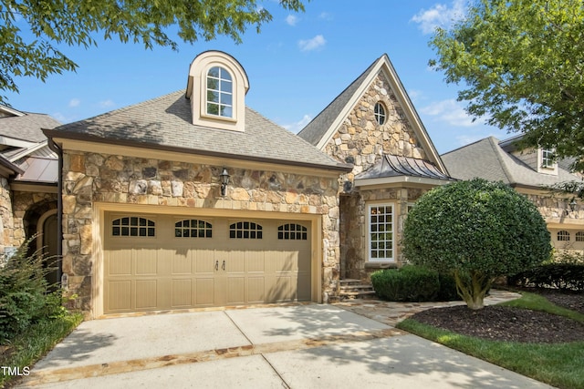 4137 Gardenlake Dr, Raleigh, NC 27612 - french country style house featuring stone siding, a standing seam roof, an attached garage, and driveway