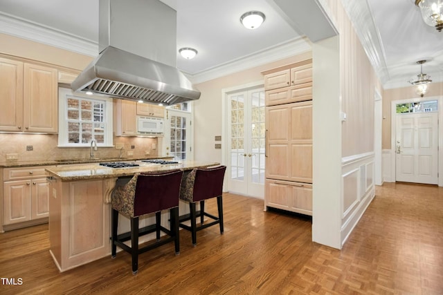 4137 Gardenlake Dr, Raleigh, NC 27612 - kitchen with island exhaust hood, light brown cabinetry, crown molding, and white microwave