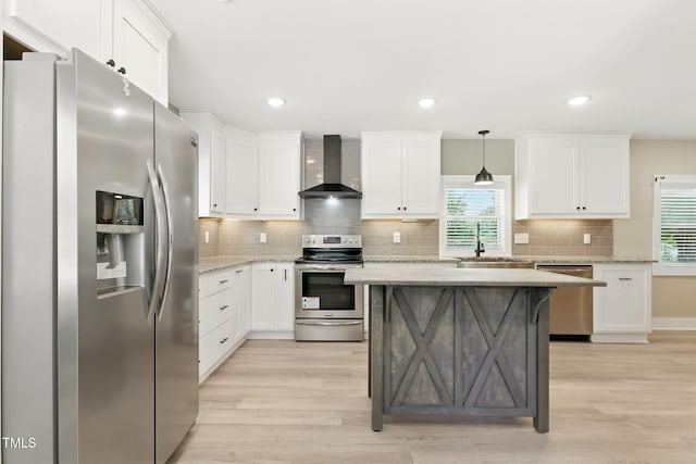 7722 NC-27, Lillington, NC 27546 - kitchen featuring appliances with stainless steel finishes, wall chimney range hood, light wood-style flooring, backsplash, and white cabinetry