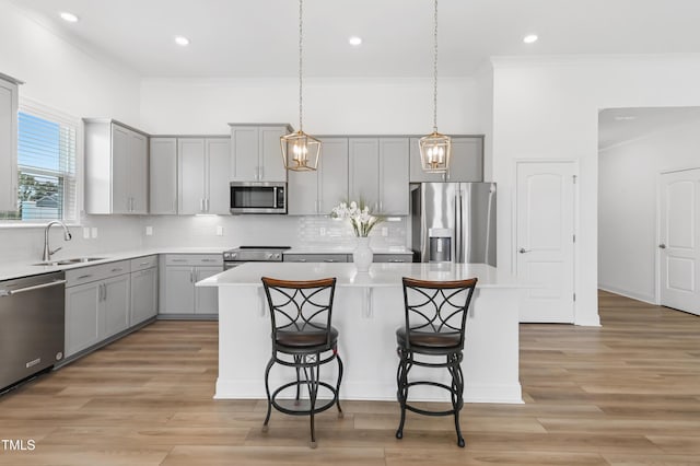 6109 Oak Passage Dr, Raleigh, NC 27603 - kitchen featuring stainless steel appliances, gray cabinetry, a kitchen island, a kitchen bar, and crown molding