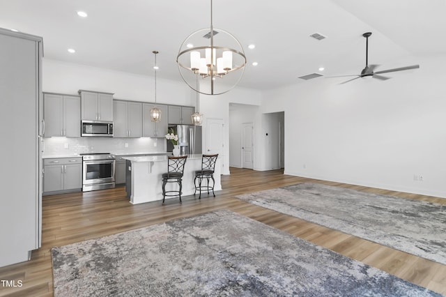 6109 Oak Passage Dr, Raleigh, NC 27603 - kitchen with stainless steel appliances, gray cabinetry, open floor plan, a kitchen island, and a high ceiling