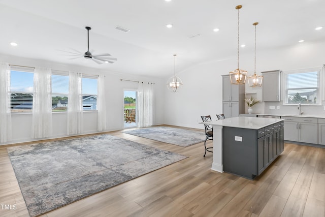 6109 Oak Passage Dr, Raleigh, NC 27603 - kitchen with gray cabinetry, ceiling fan, a kitchen island, vaulted ceiling, and light countertops