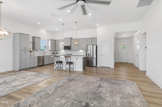 6109 Oak Passage Dr, Raleigh, NC 27603 - kitchen with gray cabinetry, stainless steel appliances, a ceiling fan, a center island, and a breakfast bar area
