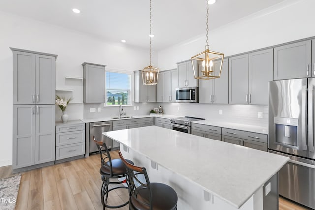 6109 Oak Passage Dr, Raleigh, NC 27603 - kitchen with appliances with stainless steel finishes, gray cabinetry, a breakfast bar, tasteful backsplash, and recessed lighting