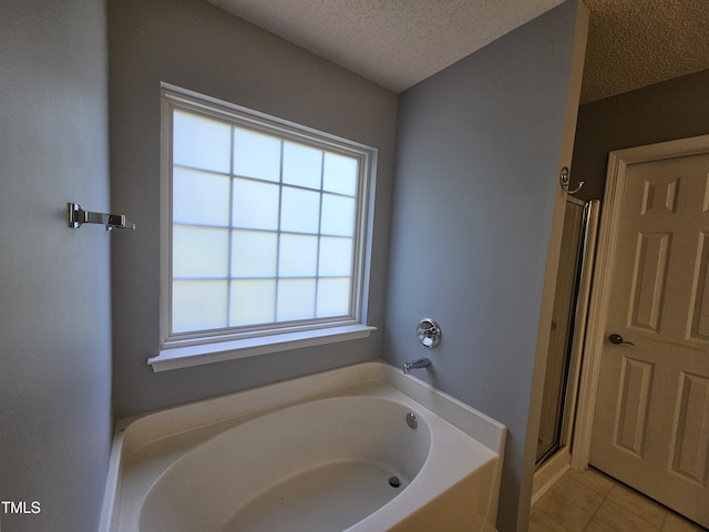 121 Brentfield Loop, Morrisville, NC 27560 - bathroom featuring a bath, a textured ceiling, healthy amount of natural light, a shower with shower door, and tile patterned flooring