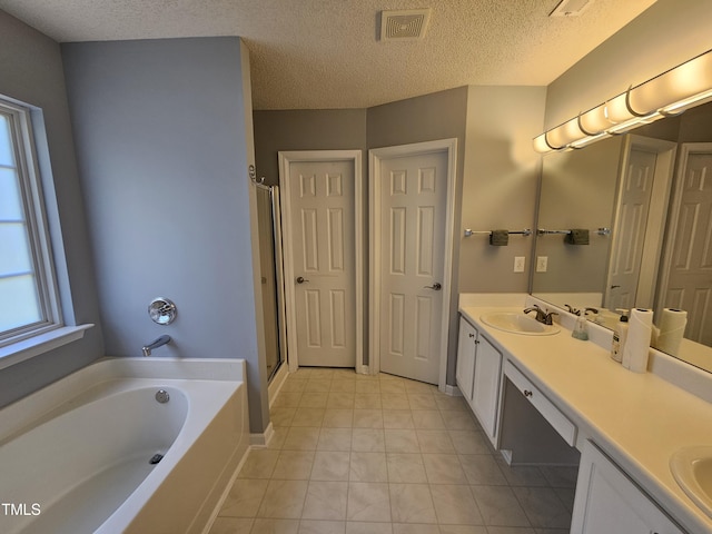 121 Brentfield Loop, Morrisville, NC 27560 - full bathroom featuring double vanity, a garden tub, a textured ceiling, a stall shower, and tile patterned floors