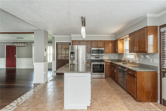 5621 Monks Walk Ct, Fayetteville, NC 28311 - kitchen featuring appliances with stainless steel finishes, a kitchen island, stone countertops, brown cabinetry, and a textured ceiling
