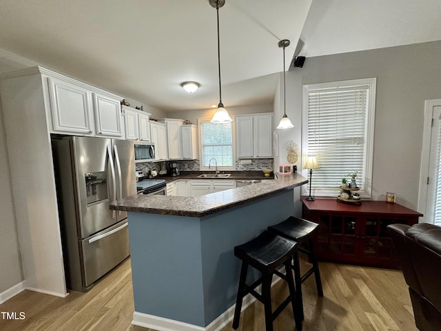 71 Beaver Creek Dr, Dunn, NC 28334 - kitchen with stainless steel appliances, a peninsula, light wood-type flooring, white cabinets, and dark countertops
