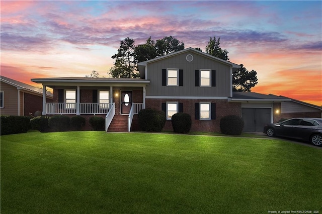 1524 Stackhouse Dr, Fayetteville, NC 28314 - tri-level home with a porch, a front yard, an attached garage, brick siding, and board and batten siding
