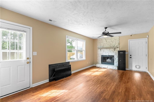 1524 Stackhouse Dr, Fayetteville, NC 28314 - unfurnished living room featuring ceiling fan, a textured ceiling, wood finished floors, and a fireplace