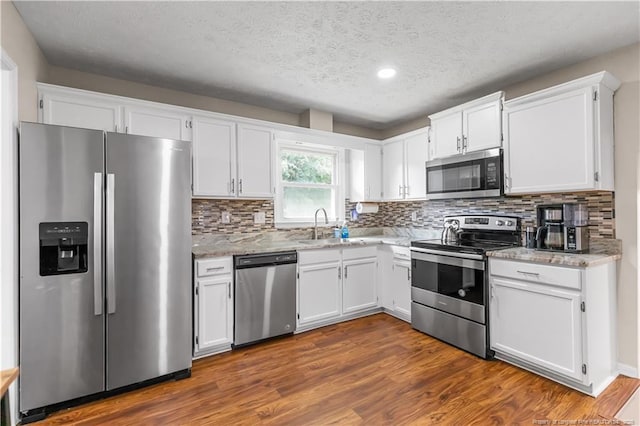 1524 Stackhouse Dr, Fayetteville, NC 28314 - kitchen featuring appliances with stainless steel finishes, white cabinets, dark wood-type flooring, a textured ceiling, and decorative backsplash