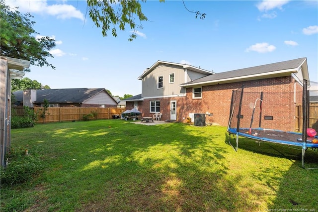 1524 Stackhouse Dr, Fayetteville, NC 28314 - back of property featuring a trampoline, brick siding, a fenced backyard, a patio, and board and batten siding