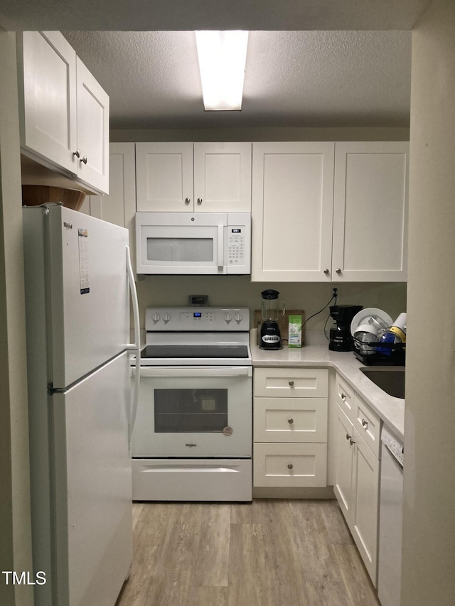 500 Umstead Dr Unit D307, Chapel Hill, NC 27516 - kitchen featuring white appliances, white cabinets, light wood-type flooring, light countertops, and a textured ceiling