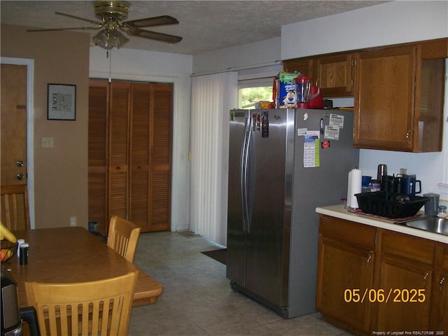 5212 Delco St, Fayetteville, NC 28311 - kitchen with freestanding refrigerator, a ceiling fan, light floors, light countertops, and brown cabinetry