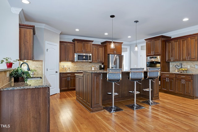 1013 Shasta Daisy Dr, Wake Forest, NC 27587 - kitchen with appliances with stainless steel finishes, backsplash, light wood finished floors, a kitchen island, and a kitchen bar