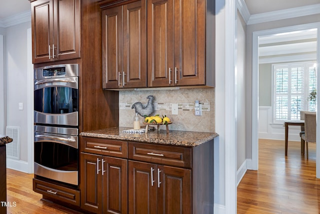 1013 Shasta Daisy Dr, Wake Forest, NC 27587 - kitchen featuring stainless steel double oven, ornamental molding, tasteful backsplash, light wood finished floors, and dark stone countertops