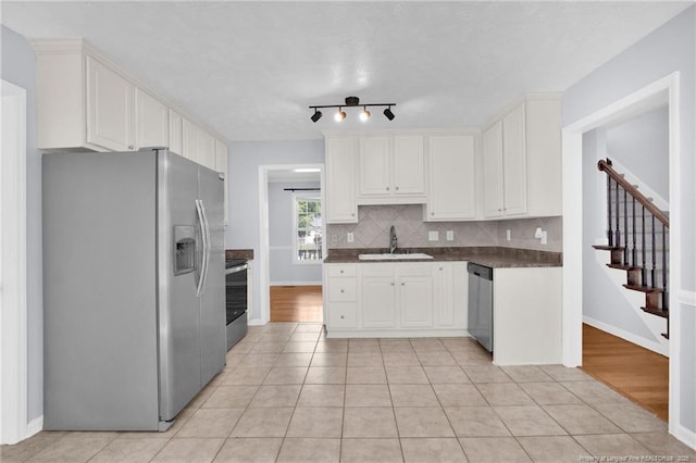 2505 Canford Ln, Fayetteville, NC 28304 - kitchen featuring stainless steel appliances, dark countertops, white cabinetry, tasteful backsplash, and light tile patterned floors
