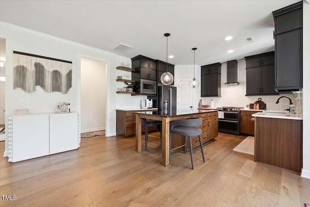 1848 Stagecoach Trl, Wendell, NC 27591 - kitchen featuring wall chimney exhaust hood, high quality appliances, light wood-style floors, a center island, and a breakfast bar