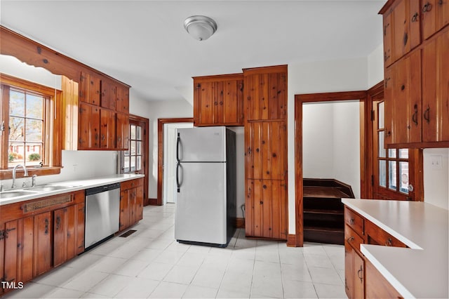 221 Whitfield St, Enfield, NC 27823 - kitchen featuring freestanding refrigerator, stainless steel dishwasher, light countertops, and brown cabinetry