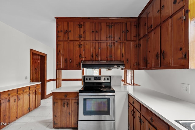 221 Whitfield St, Enfield, NC 27823 - kitchen featuring stainless steel range with electric stovetop, under cabinet range hood, light countertops, and brown cabinets