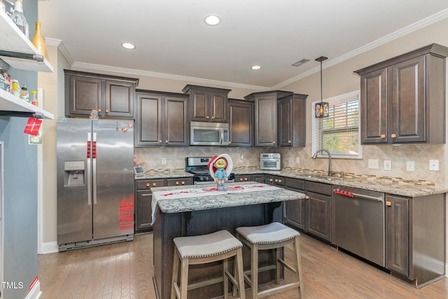 2407 Cattail Pond Dr, Zebulon, NC 27597 - kitchen featuring stainless steel appliances, dark brown cabinets, hardwood / wood-style floors, light stone countertops, and crown molding