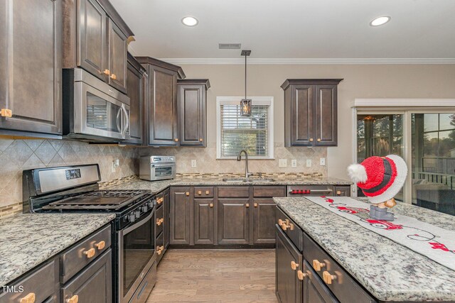 2407 Cattail Pond Dr, Zebulon, NC 27597 - kitchen with appliances with stainless steel finishes, dark brown cabinets, light wood-type flooring, light stone counters, and recessed lighting