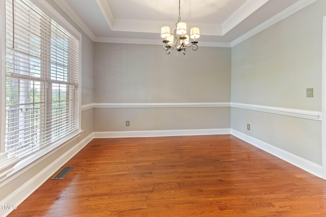 8508 Parlange Woods Ln, Wake Forest, NC 27587 - empty room featuring plenty of natural light, a chandelier, a raised ceiling, wood finished floors, and crown molding