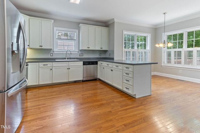 8508 Parlange Woods Ln, Wake Forest, NC 27587 - kitchen with appliances with stainless steel finishes, dark countertops, a peninsula, healthy amount of natural light, and ornamental molding
