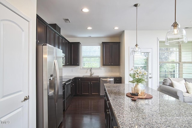 21 Intuition Cir, Durham, NC 27705 - kitchen featuring appliances with stainless steel finishes, light stone counters, backsplash, dark brown cabinets, and dark wood-style floors