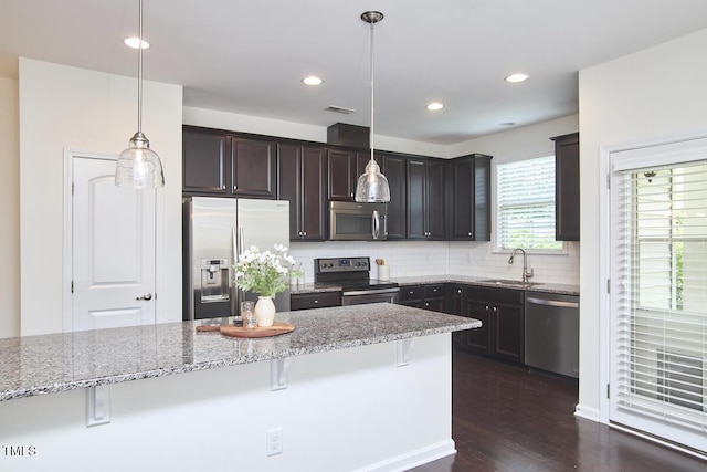 21 Intuition Cir, Durham, NC 27705 - kitchen with appliances with stainless steel finishes, a breakfast bar, light stone counters, backsplash, and dark wood-style floors