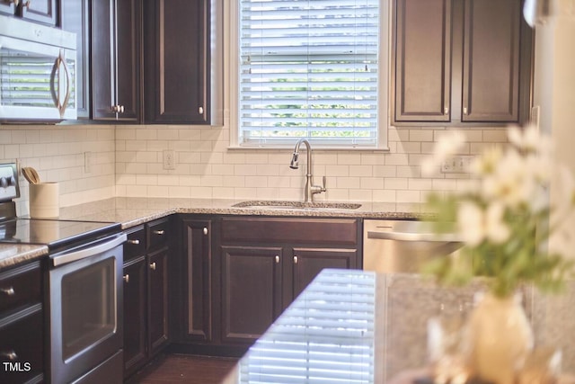 21 Intuition Cir, Durham, NC 27705 - kitchen featuring appliances with stainless steel finishes, tasteful backsplash, light stone countertops, and dark brown cabinets