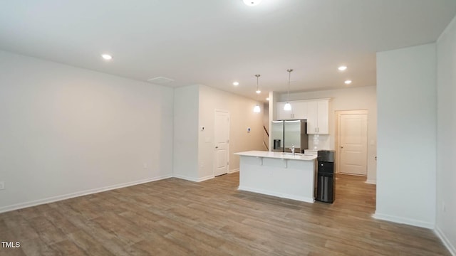 103 Liam St Unit 108, Clayton, NC 27520 - kitchen featuring a kitchen island with sink, wood finished floors, stainless steel refrigerator with ice dispenser, white cabinets, and recessed lighting