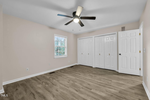 2233 Alpine Rd, Durham, NC 27707 - unfurnished bedroom with two closets, wood finished floors, and ceiling fan