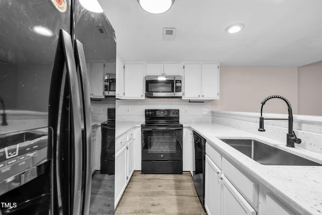 2233 Alpine Rd, Durham, NC 27707 - kitchen with black appliances, light wood finished floors, white cabinetry, light stone counters, and decorative backsplash