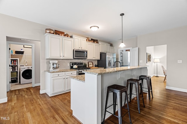 20 Kola Nut, Smithfield, NC 27577 - kitchen with stainless steel appliances, washer / clothes dryer, a kitchen island with sink, and white cabinets