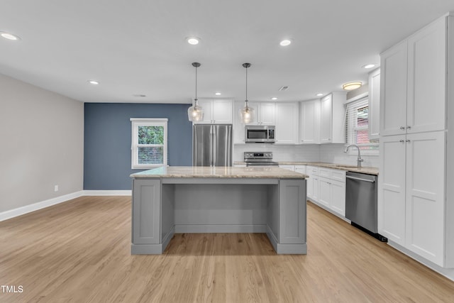 1316 Foxrun Dr, Raleigh, NC 27610 - kitchen with appliances with stainless steel finishes, white cabinetry, light wood finished floors, decorative backsplash, and a center island