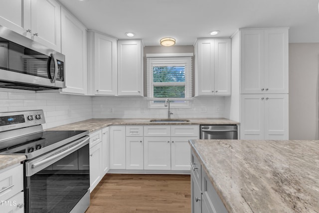 1316 Foxrun Dr, Raleigh, NC 27610 - kitchen with appliances with stainless steel finishes, light wood-type flooring, white cabinetry, backsplash, and recessed lighting