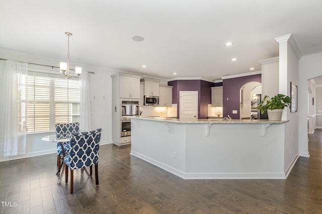4611 Lazy Hollow Dr, Knightdale, NC 27545 - kitchen featuring appliances with stainless steel finishes, a breakfast bar, light stone countertops, crown molding, and dark wood-type flooring
