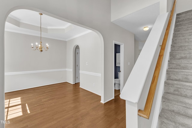 5513 Enoree Ln, Raleigh, NC 27616 - interior space featuring arched walkways, wood finished floors, a raised ceiling, crown molding, and a chandelier