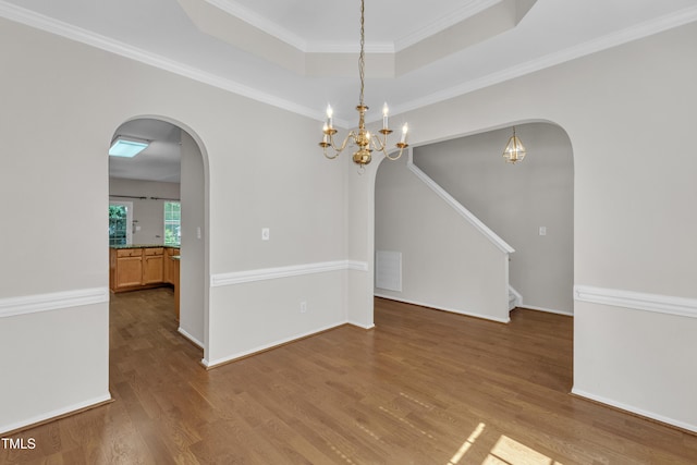 5513 Enoree Ln, Raleigh, NC 27616 - empty room featuring arched walkways, a raised ceiling, wood finished floors, a chandelier, and stairway