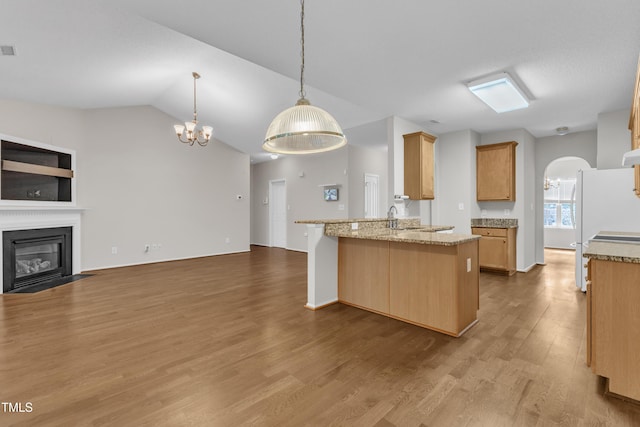 5513 Enoree Ln, Raleigh, NC 27616 - kitchen with open floor plan, a chandelier, a glass covered fireplace, a peninsula, and wood finished floors
