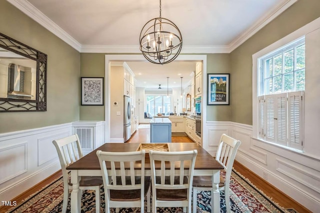 1213 Pierce St, Raleigh, NC 27605 - dining area featuring a chandelier, plenty of natural light, light wood-style flooring, a decorative wall, and crown molding