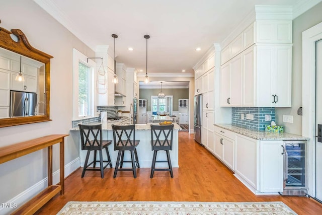 1213 Pierce St, Raleigh, NC 27605 - kitchen featuring freestanding refrigerator, wine cooler, white cabinets, tasteful backsplash, and crown molding