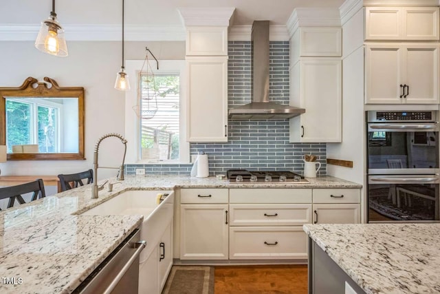 1213 Pierce St, Raleigh, NC 27605 - kitchen featuring wall chimney range hood, appliances with stainless steel finishes, decorative backsplash, light stone countertops, and hanging light fixtures