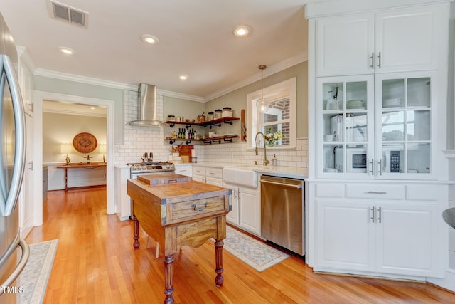 10781 US-158, Reidsville, NC 27320 - kitchen with stainless steel appliances, wall chimney range hood, light countertops, white cabinetry, and ornamental molding