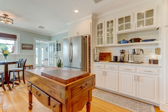 10781 US-158, Reidsville, NC 27320 - kitchen with freestanding refrigerator, light wood-type flooring, backsplash, white cabinetry, and glass insert cabinets
