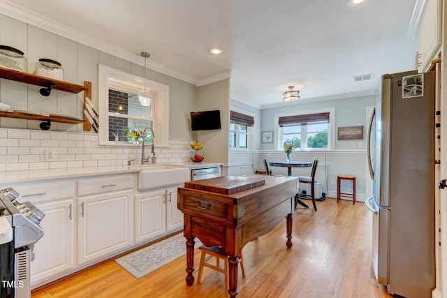 10781 US-158, Reidsville, NC 27320 - kitchen featuring stainless steel appliances, ornamental molding, white cabinetry, light countertops, and light wood finished floors