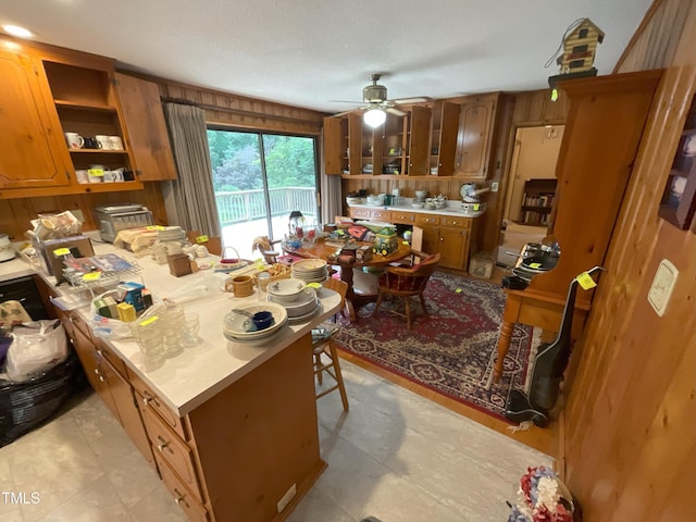 5924 Woodcrest Dr, Raleigh, NC 27603 - kitchen featuring brown cabinets, open shelves, wood walls, ceiling fan, and light countertops