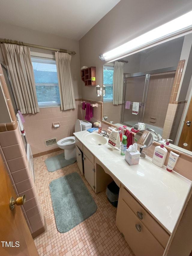 5924 Woodcrest Dr, Raleigh, NC 27603 - full bathroom featuring tile walls, vanity, tile patterned floors, enclosed tub / shower combo, and wainscoting