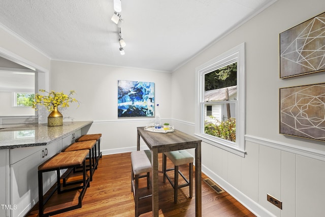 7 Meadowbrook Ave, Durham, NC 27712 - dining area featuring wood finished floors, a wainscoted wall, ornamental molding, and track lighting